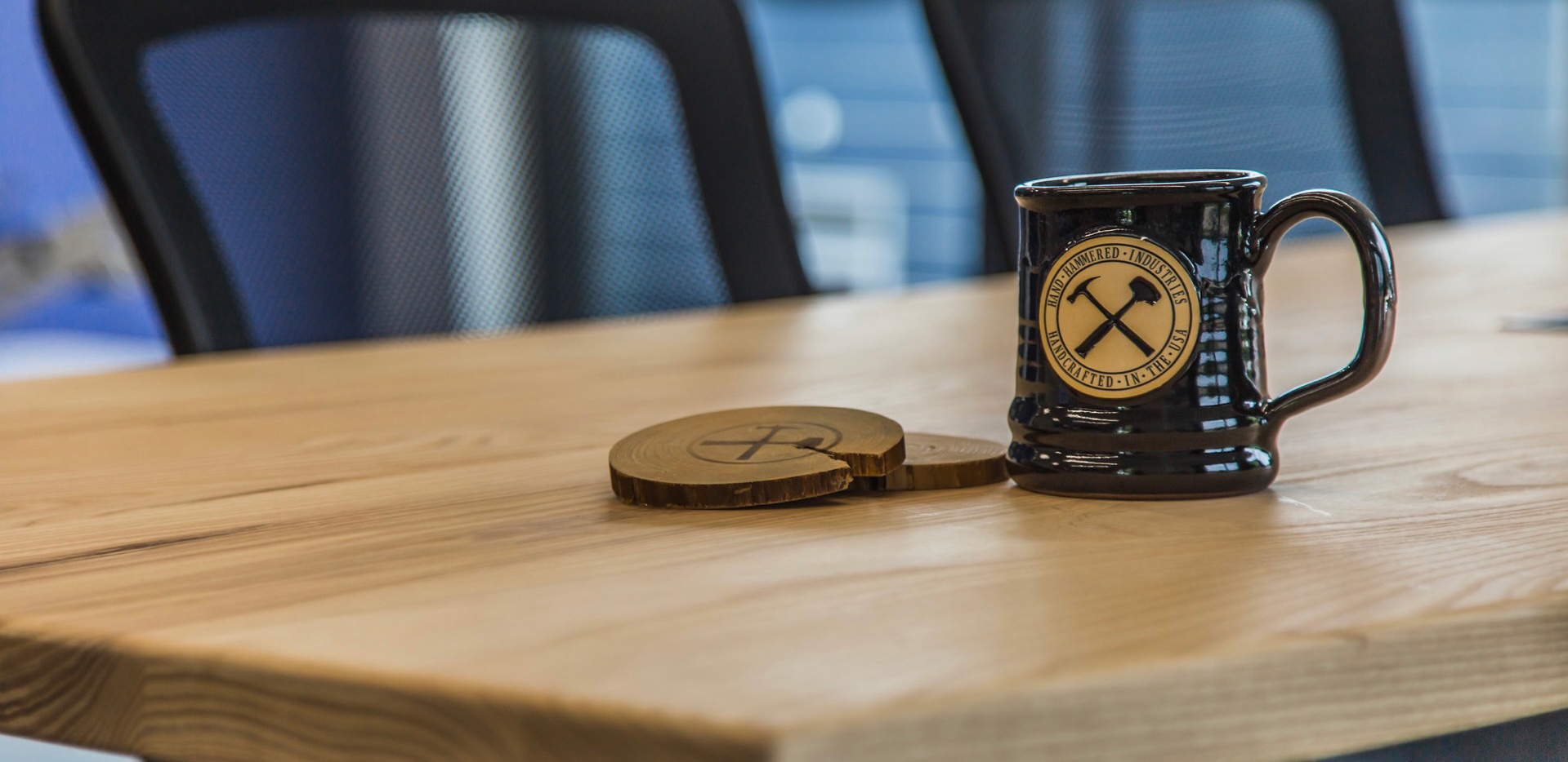 Hand Hammered mug and branded coaster on a desk