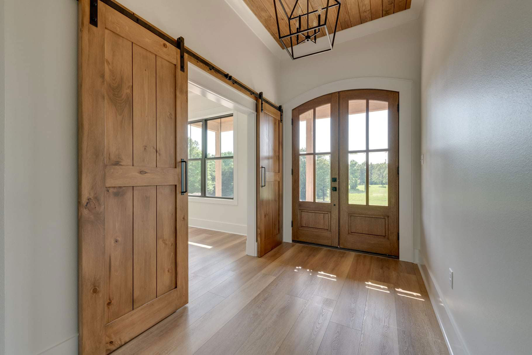 Bright entryway with custom wood front doors and barn doors leading into the dining room