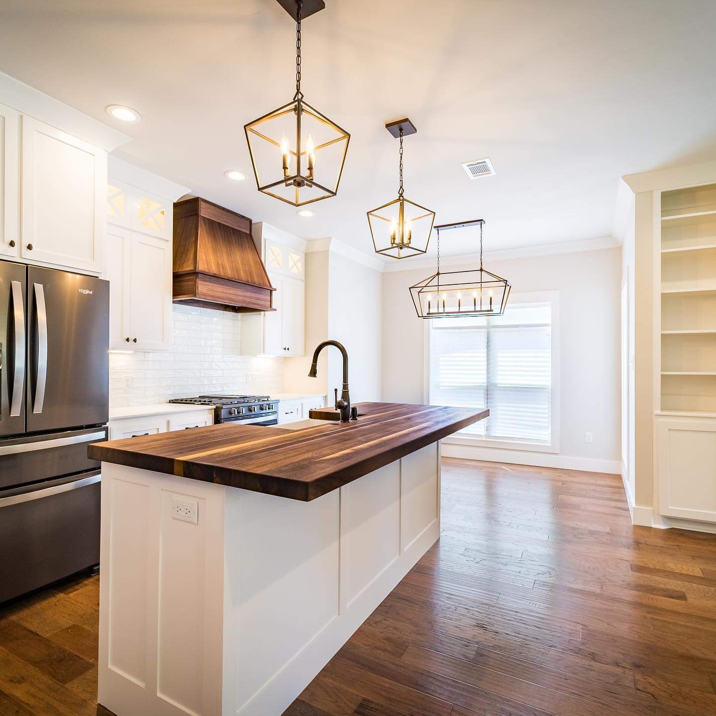 Bright white kitchen with brass accents and custom butcher block countertop
